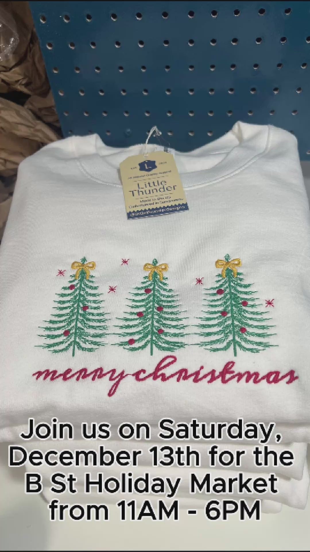 Timelapse video of three evergreen trees being embroidered onto a white crewneck sweatshirt with Merry Christmas in a handwritten-style script embroidered in red below the trees. 